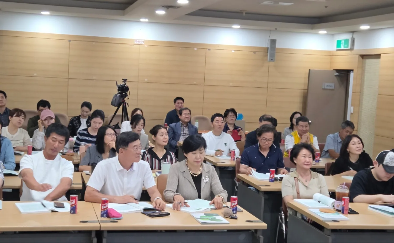 오프라인 교육 현장 — 수강생들이 강의를 듣고 있고 뒤쪽에 촬영용 카메라가 설치되어 있다